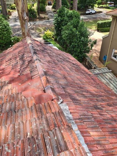 Roofer inspecting flashing around a chimney looking for the source of a leak
